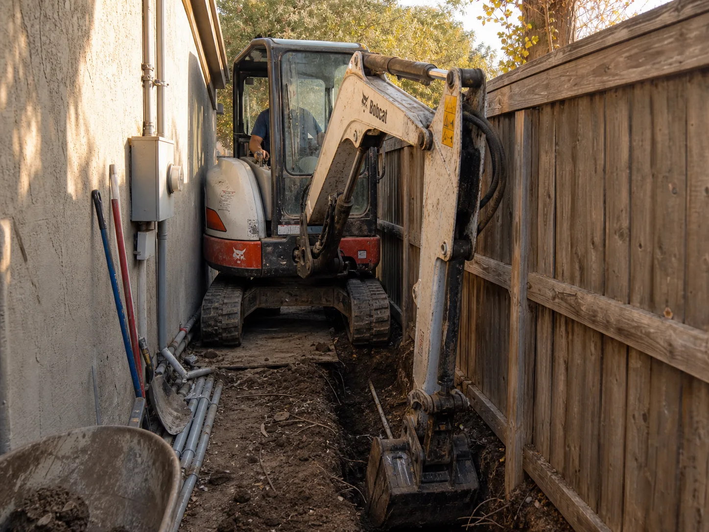 Compact zero-tail-swing excavator trenching in a narrow side yard